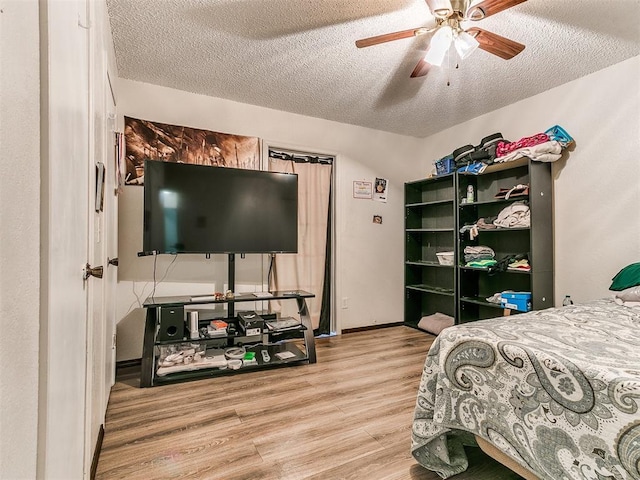 bedroom featuring ceiling fan, baseboards, a textured ceiling, and wood finished floors