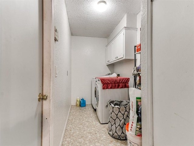 clothes washing area with a textured ceiling, cabinet space, baseboards, and washer and clothes dryer