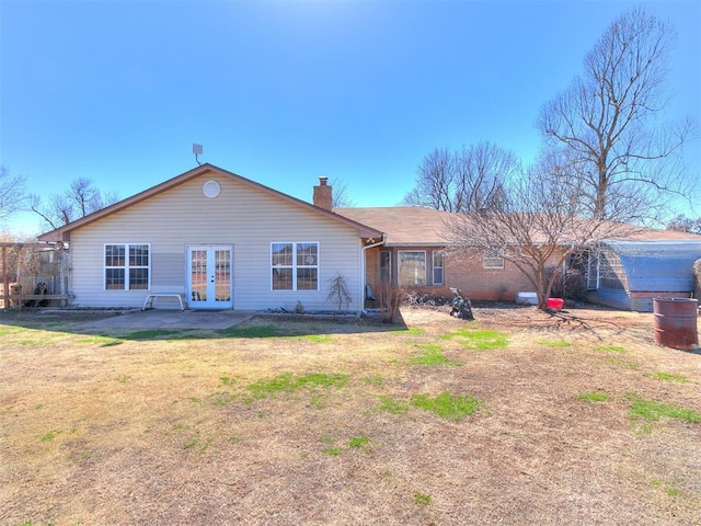 rear view of house featuring a patio, french doors, a lawn, and a chimney