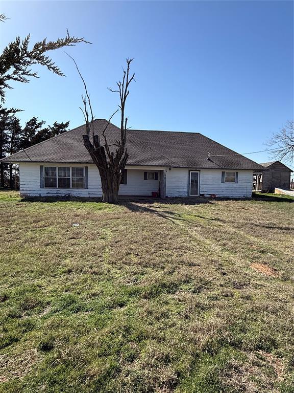 view of front of home featuring a front lawn and a shingled roof