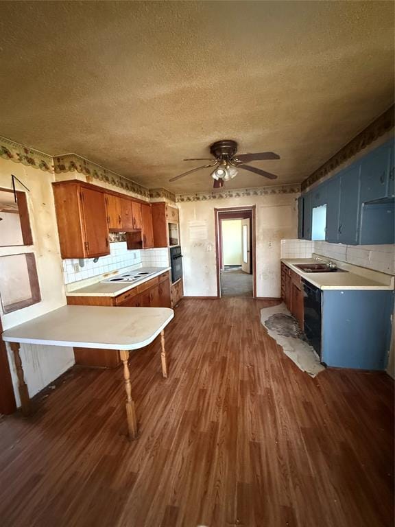 kitchen with ceiling fan, dark wood-style floors, brown cabinetry, and light countertops