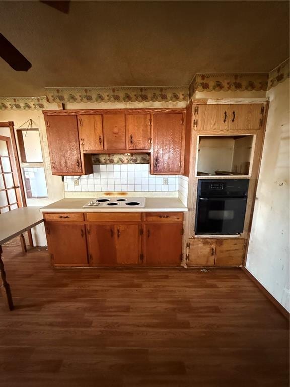 kitchen with white electric cooktop, oven, dark wood-type flooring, and light countertops