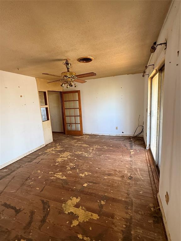 unfurnished room with ceiling fan, visible vents, and a textured ceiling