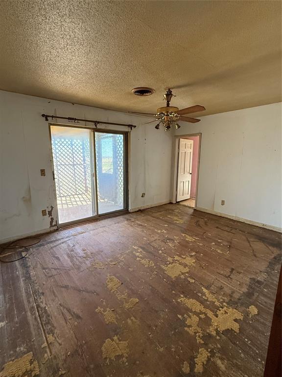 spare room featuring visible vents, baseboards, ceiling fan, wood finished floors, and a textured ceiling