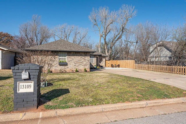 view of side of home with driveway, fence, a yard, a shingled roof, and brick siding