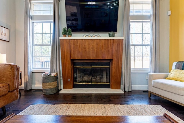 living room featuring a glass covered fireplace, baseboards, and hardwood / wood-style floors