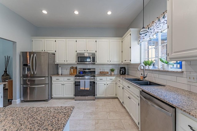 kitchen with a sink, tasteful backsplash, white cabinetry, stainless steel appliances, and light stone countertops