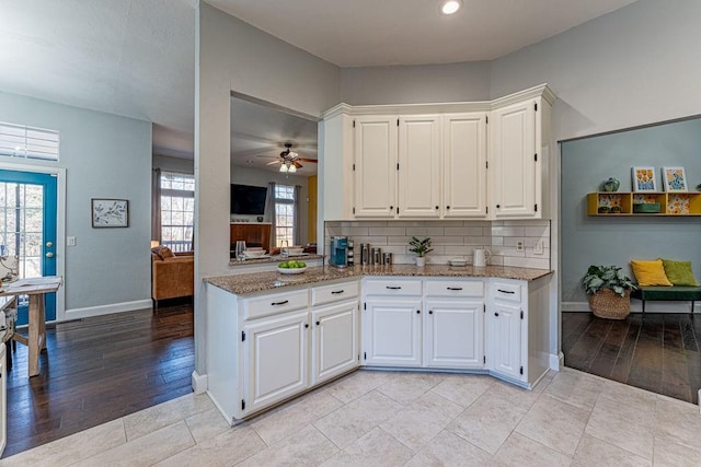 kitchen featuring light wood-style flooring, backsplash, white cabinets, light stone countertops, and ceiling fan