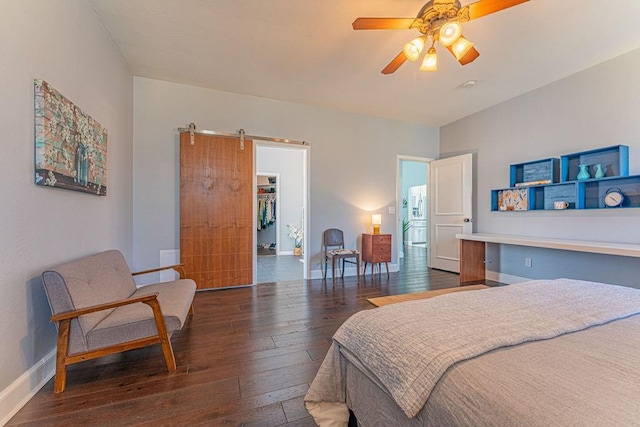 bedroom featuring a ceiling fan, baseboards, hardwood / wood-style flooring, a spacious closet, and a barn door