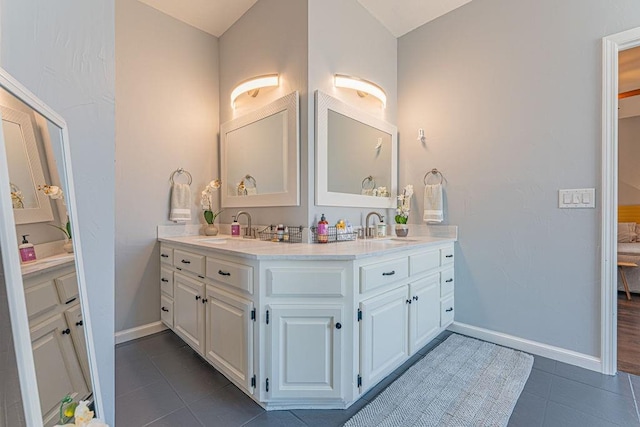 full bath featuring a sink, baseboards, double vanity, and tile patterned flooring