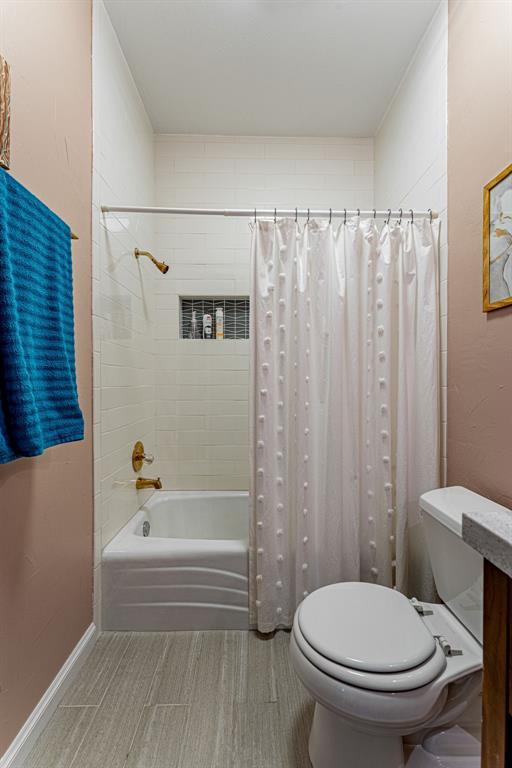 full bathroom featuring toilet, baseboards, and shower / bath combo