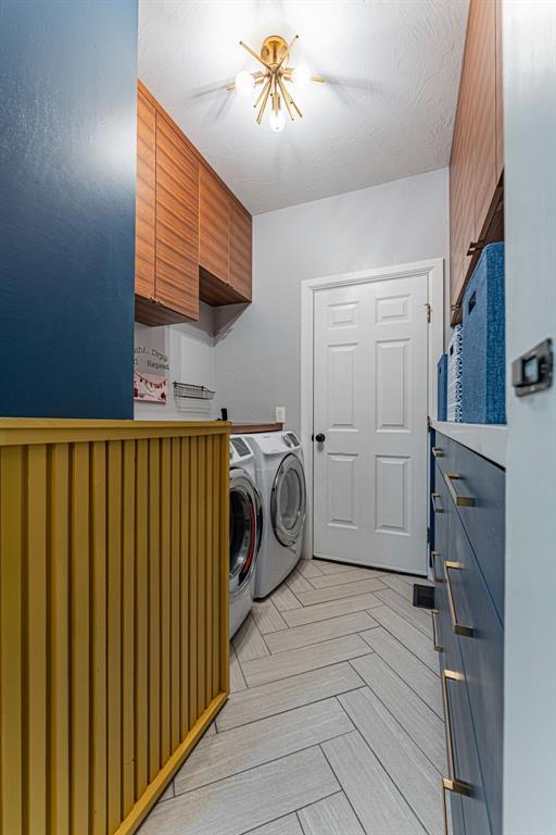 washroom featuring an inviting chandelier, cabinet space, and separate washer and dryer