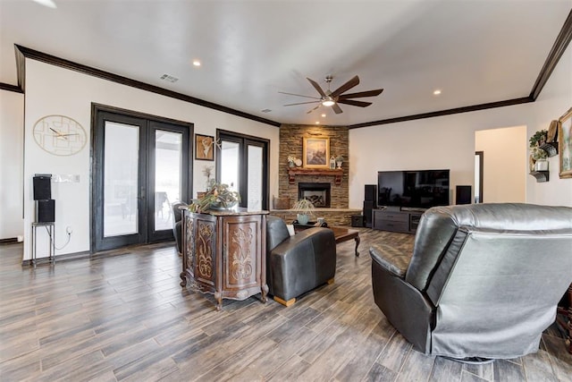 living area featuring french doors, a ceiling fan, crown molding, wood finished floors, and a stone fireplace