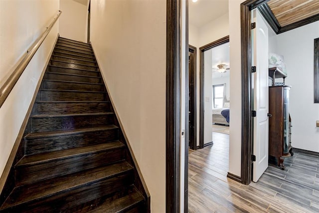staircase featuring wood finished floors and baseboards