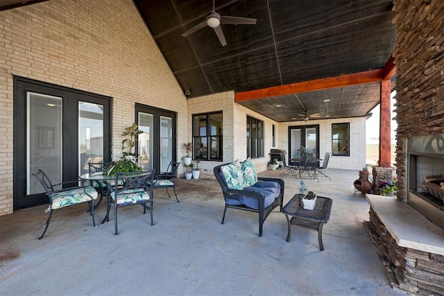 view of patio / terrace featuring a large fireplace, ceiling fan, outdoor dining area, and french doors