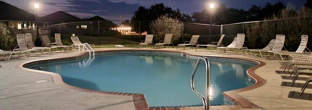 11305 NW 103rd St, Yukon, OK 73099 - pool at night featuring a patio area, fence, and a community pool