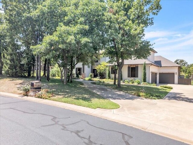 obstructed view of property with stucco siding, a garage, a front lawn, and concrete driveway