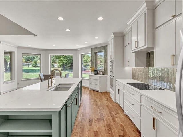 kitchen with black electric cooktop, ornamental molding, decorative backsplash, a sink, and light wood-style floors