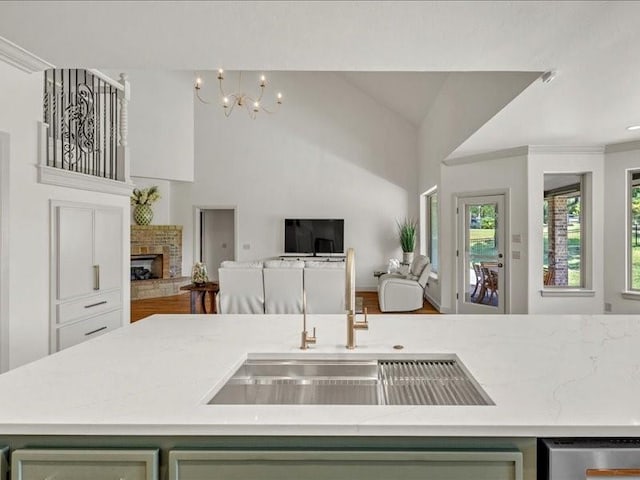 kitchen featuring a fireplace with raised hearth, a sink, an inviting chandelier, and open floor plan