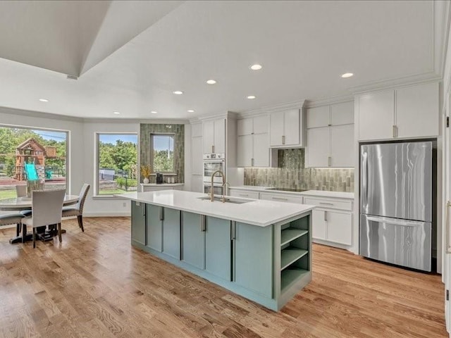 kitchen featuring freestanding refrigerator, light countertops, a sink, and white cabinetry