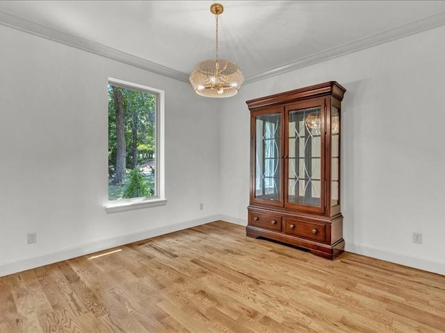 empty room with baseboards, an inviting chandelier, crown molding, and light wood finished floors