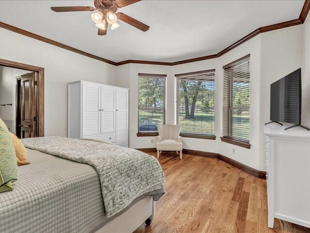 bedroom with baseboards, light wood-type flooring, crown molding, and ceiling fan