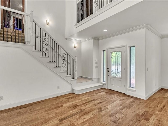 entryway with baseboards, wood finished floors, stairway, and crown molding