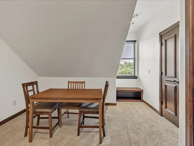 dining area featuring light carpet, baseboards, lofted ceiling, and visible vents