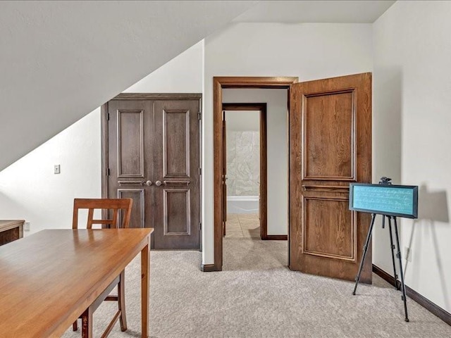 office featuring baseboards, lofted ceiling, and light colored carpet