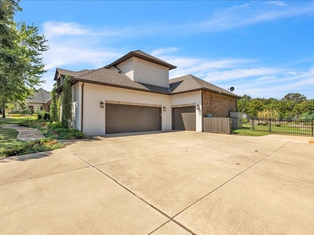 view of front of property featuring driveway, an attached garage, fence, and stucco siding
