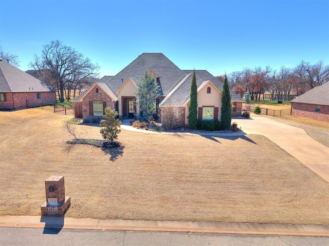 view of front of property featuring stone siding, stucco siding, concrete driveway, and fence