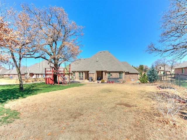 back of house with a playground, a lawn, and fence