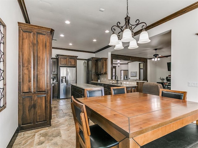 dining area with stone finish floor, recessed lighting, ceiling fan with notable chandelier, and ornamental molding