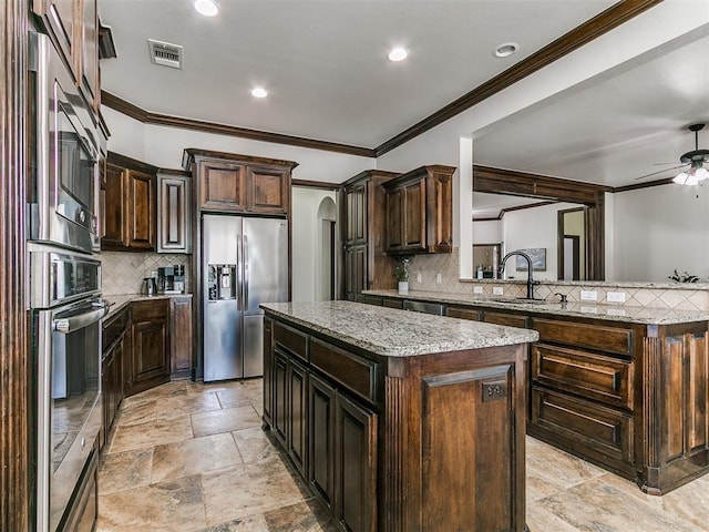 kitchen featuring a kitchen island, light stone countertops, arched walkways, stainless steel appliances, and a ceiling fan