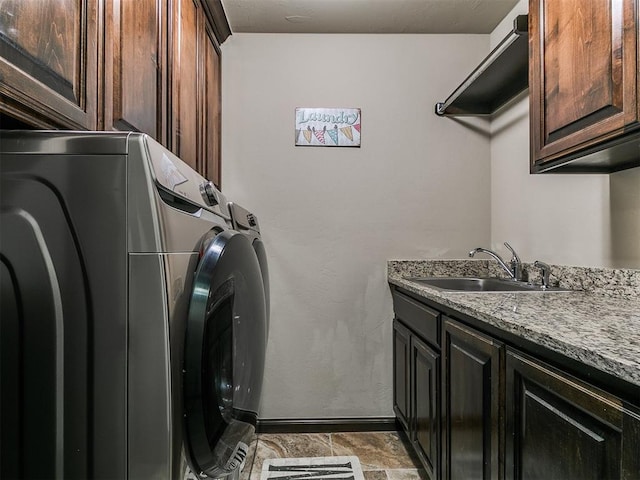 laundry area featuring a sink, baseboards, cabinet space, and washing machine and dryer