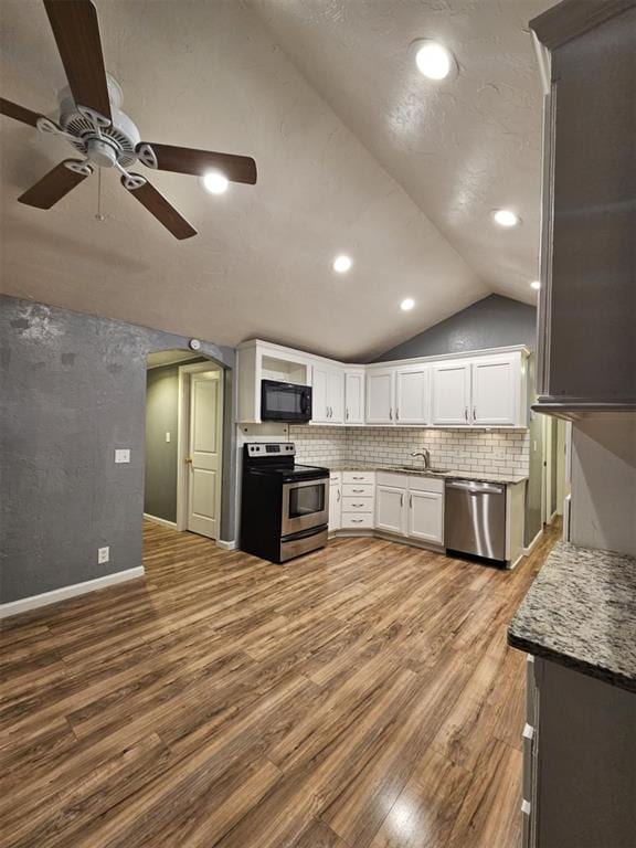 kitchen featuring ceiling fan, dark wood finished floors, vaulted ceiling, appliances with stainless steel finishes, and white cabinets