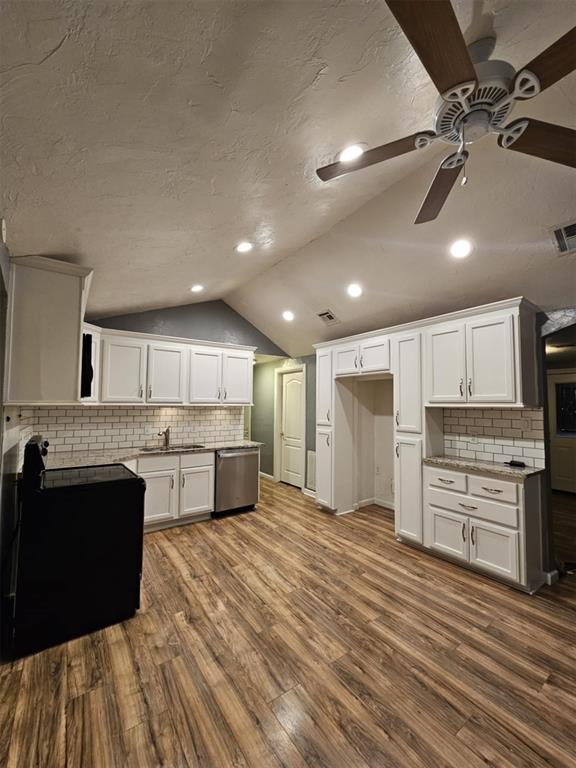 kitchen with a sink, dishwasher, lofted ceiling, a ceiling fan, and dark wood-style flooring