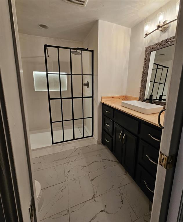 full bath with walk in shower, visible vents, marble finish floor, and vanity