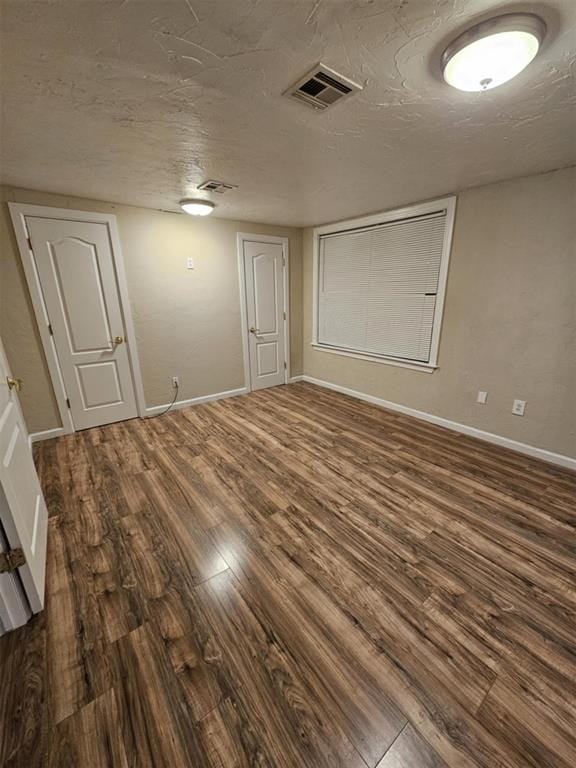 spare room featuring visible vents, baseboards, a textured ceiling, and wood finished floors