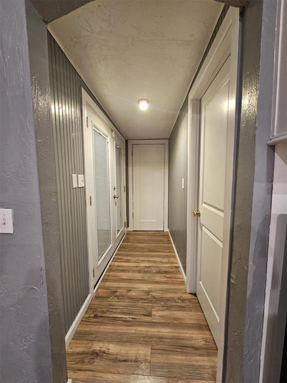 hall with a textured wall and wood finished floors