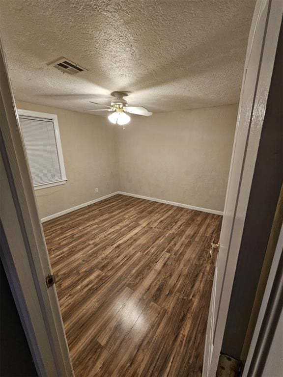 spare room with visible vents, baseboards, ceiling fan, dark wood-style floors, and a textured ceiling