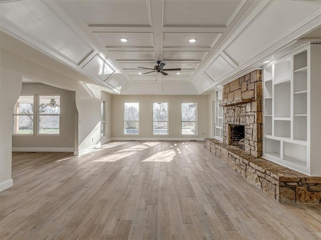 unfurnished living room featuring a wealth of natural light, coffered ceiling, ceiling fan, and a fireplace