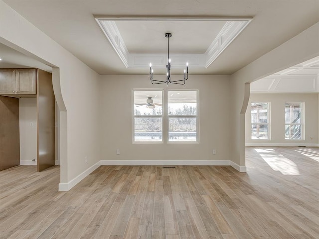 unfurnished dining area featuring a tray ceiling, light wood-style floors, and baseboards