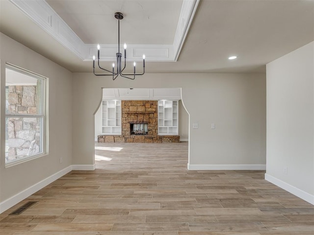 unfurnished dining area with visible vents, baseboards, light wood-style floors, a notable chandelier, and a raised ceiling