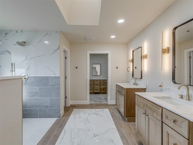 full bath with wood finished floors, two vanities, walk in shower, and a sink