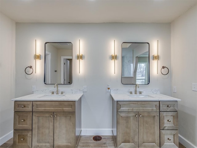 bathroom featuring two vanities, baseboards, and a sink