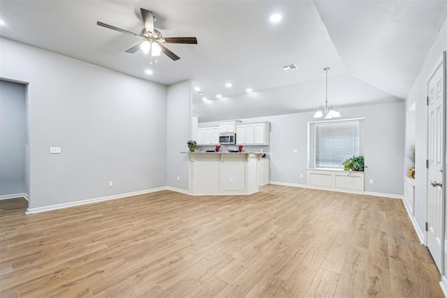 unfurnished living room with visible vents, light wood finished floors, baseboards, lofted ceiling, and ceiling fan with notable chandelier