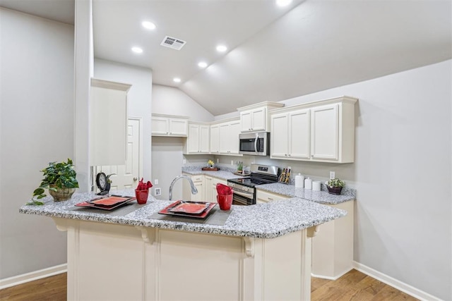 kitchen with visible vents, light wood finished floors, recessed lighting, appliances with stainless steel finishes, and a kitchen breakfast bar