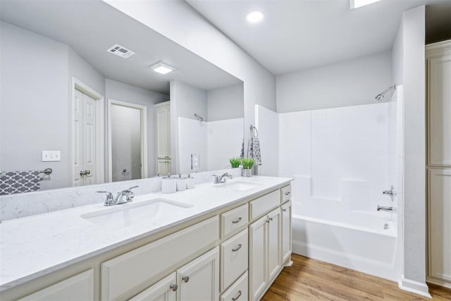 bathroom featuring a sink, visible vents, wood finished floors, and double vanity