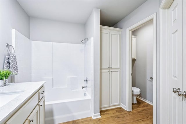 full bath featuring vanity, washtub / shower combination, wood finished floors, baseboards, and toilet